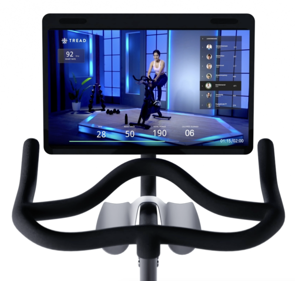 Android Tab attached to a spinning bike and a spinning instructor taking taking a class